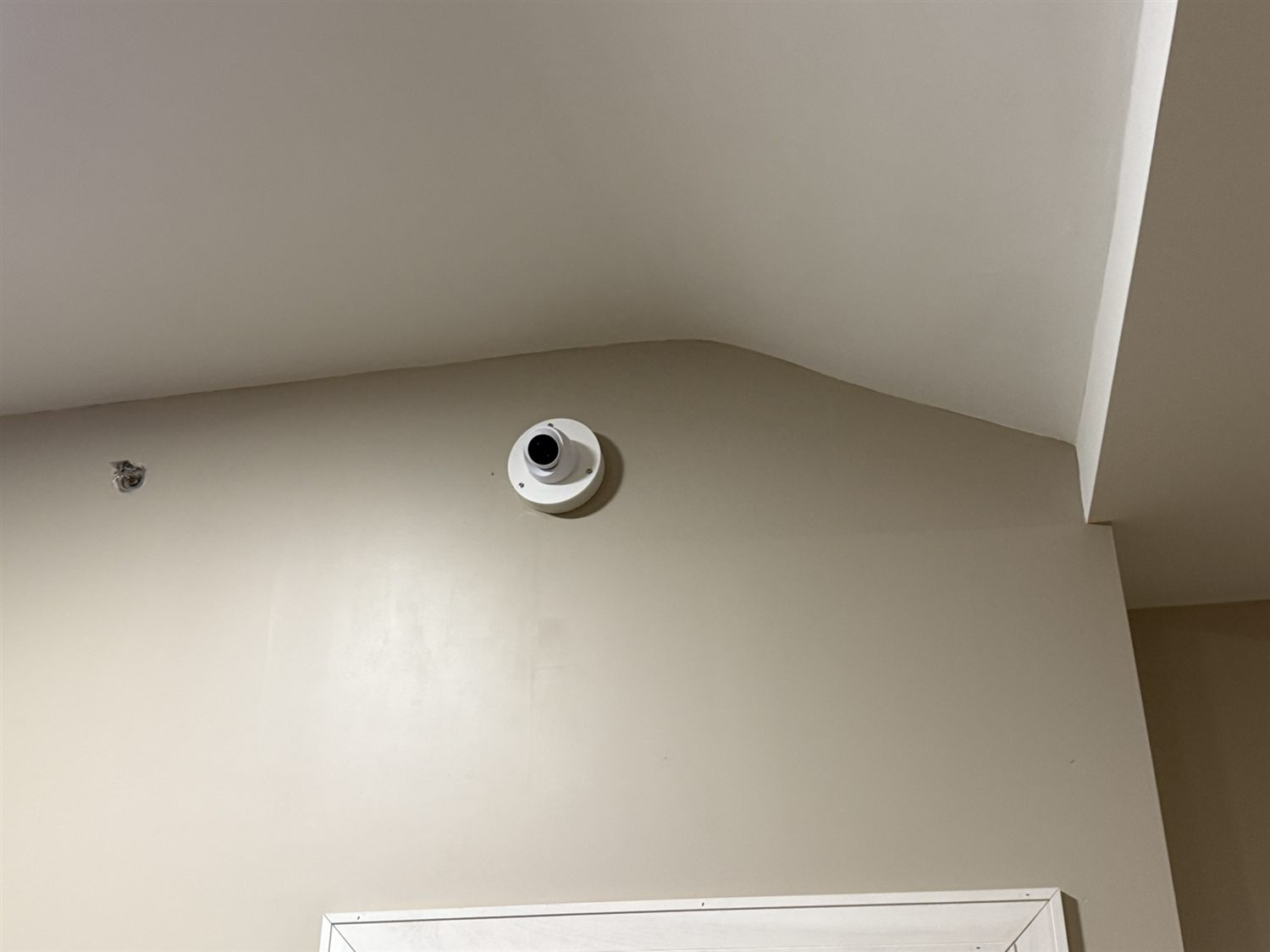Wall-mounted turret security camera installed near a ceiling